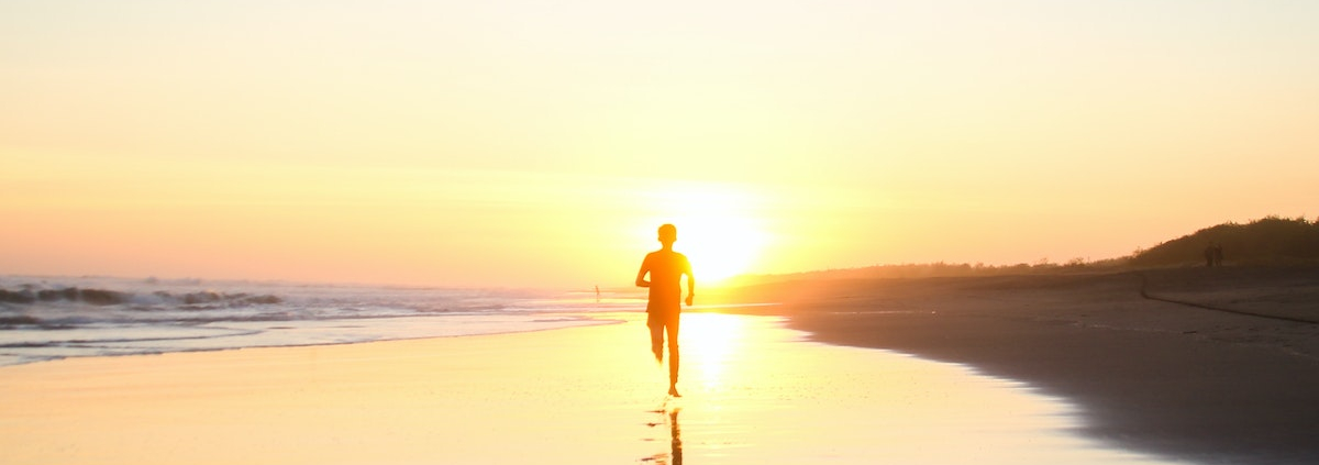 Silhouette of Boy Running in Body of Water during Sunset